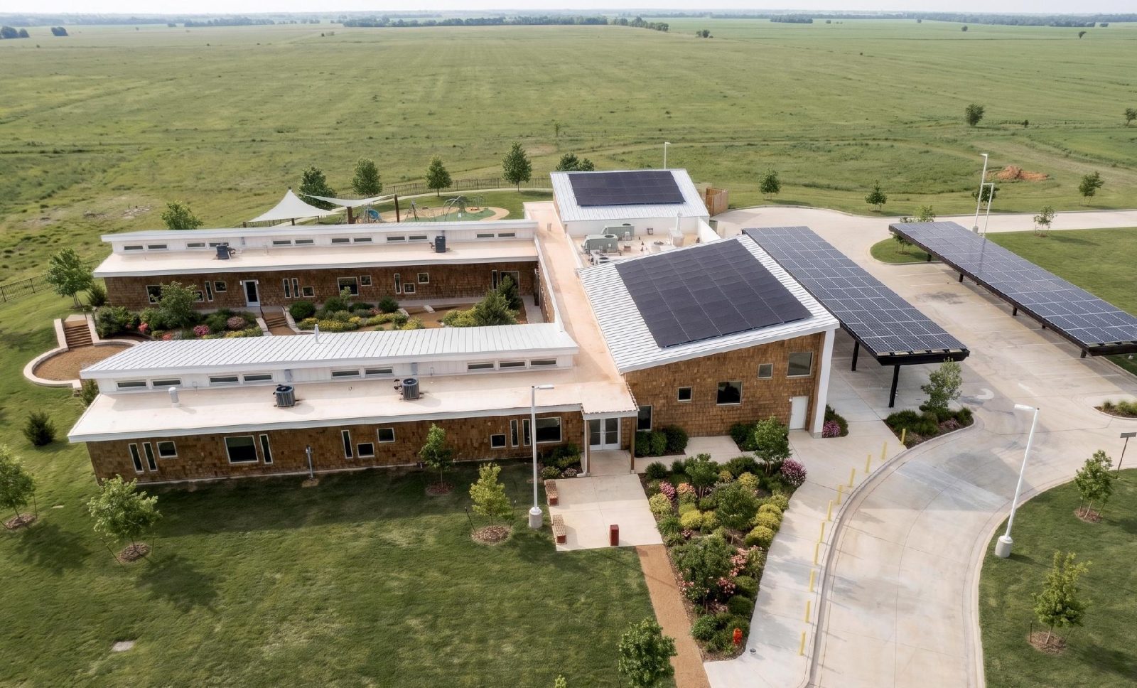 Aerial view of solar carports beside a rural facility with metal roofs and solar panels