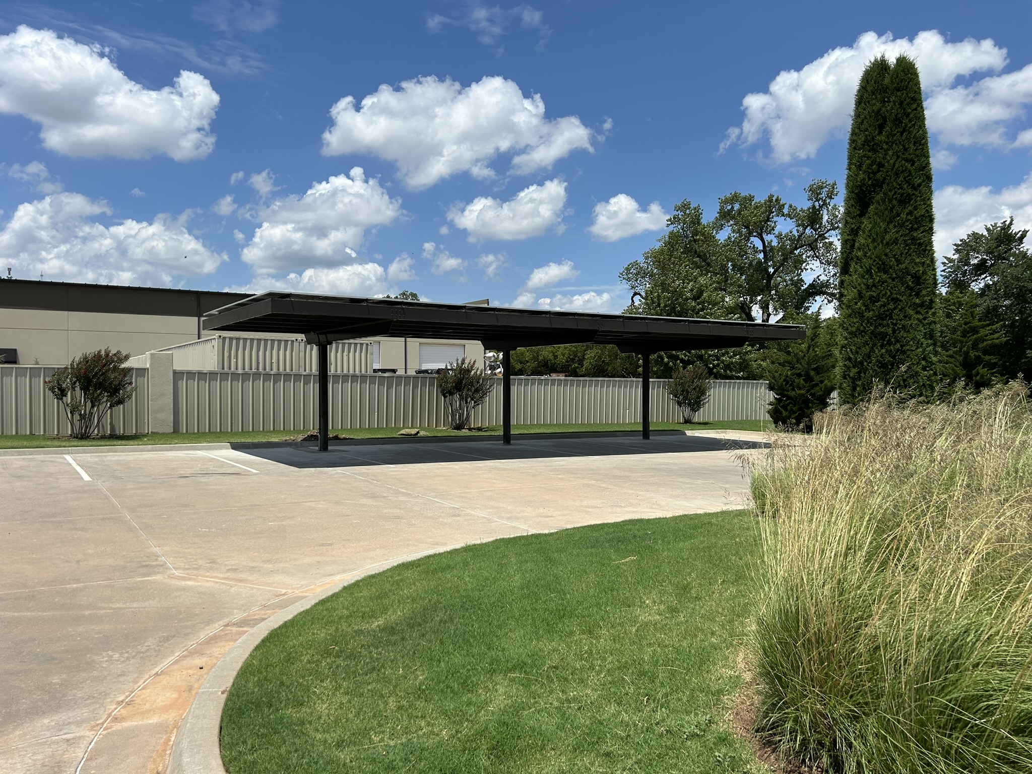 Finished black cantilever carport over a landscaped commercial parking area